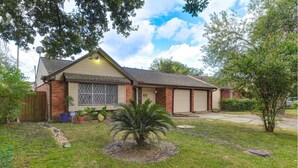 A single-story house with a garage, a front yard with a palm tree, and a brick exterior. - Perfect home away from home. Excellent weekend getaway. (Houston)