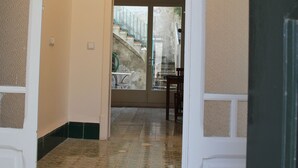 Un couloir avec des carreaux de sol à motifs, une porte donnant sur un escalier et un luminaire au plafond.