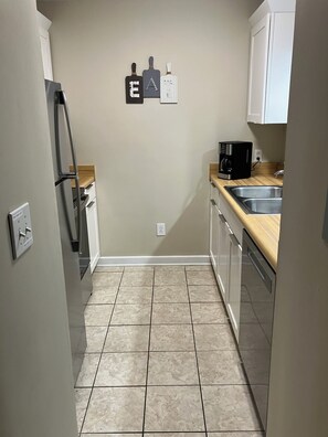 A compact kitchen with a refrigerator, a coffee maker, and a sink.
