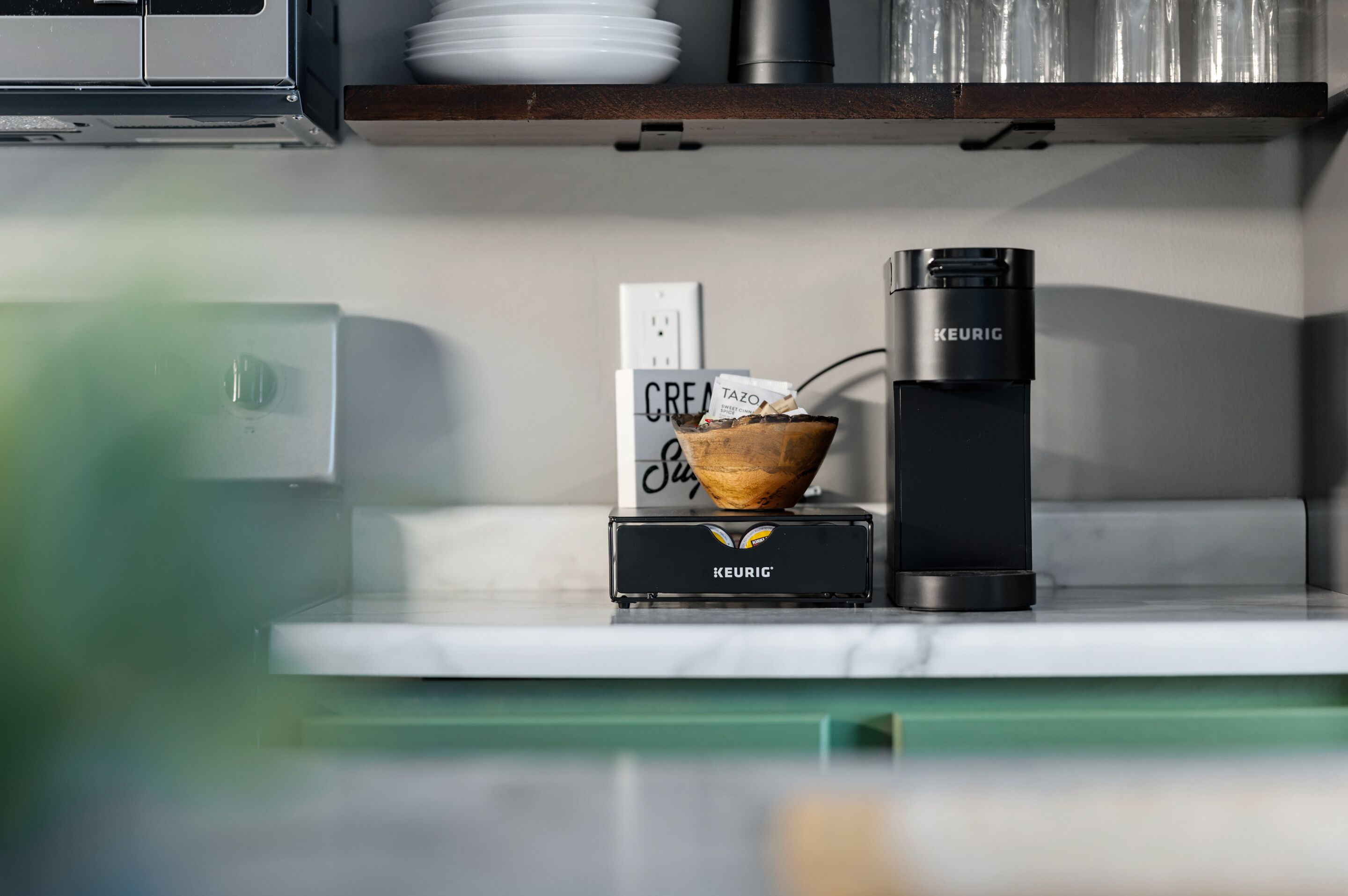 A kitchen counter with a Keurig coffee maker, a coffee pod box, and a coffee pot.