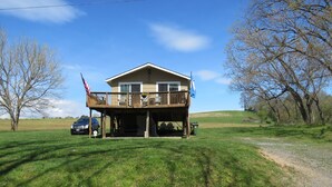 Une maison à deux étages avec un balcon, un drapeau et une voiture garée devant.