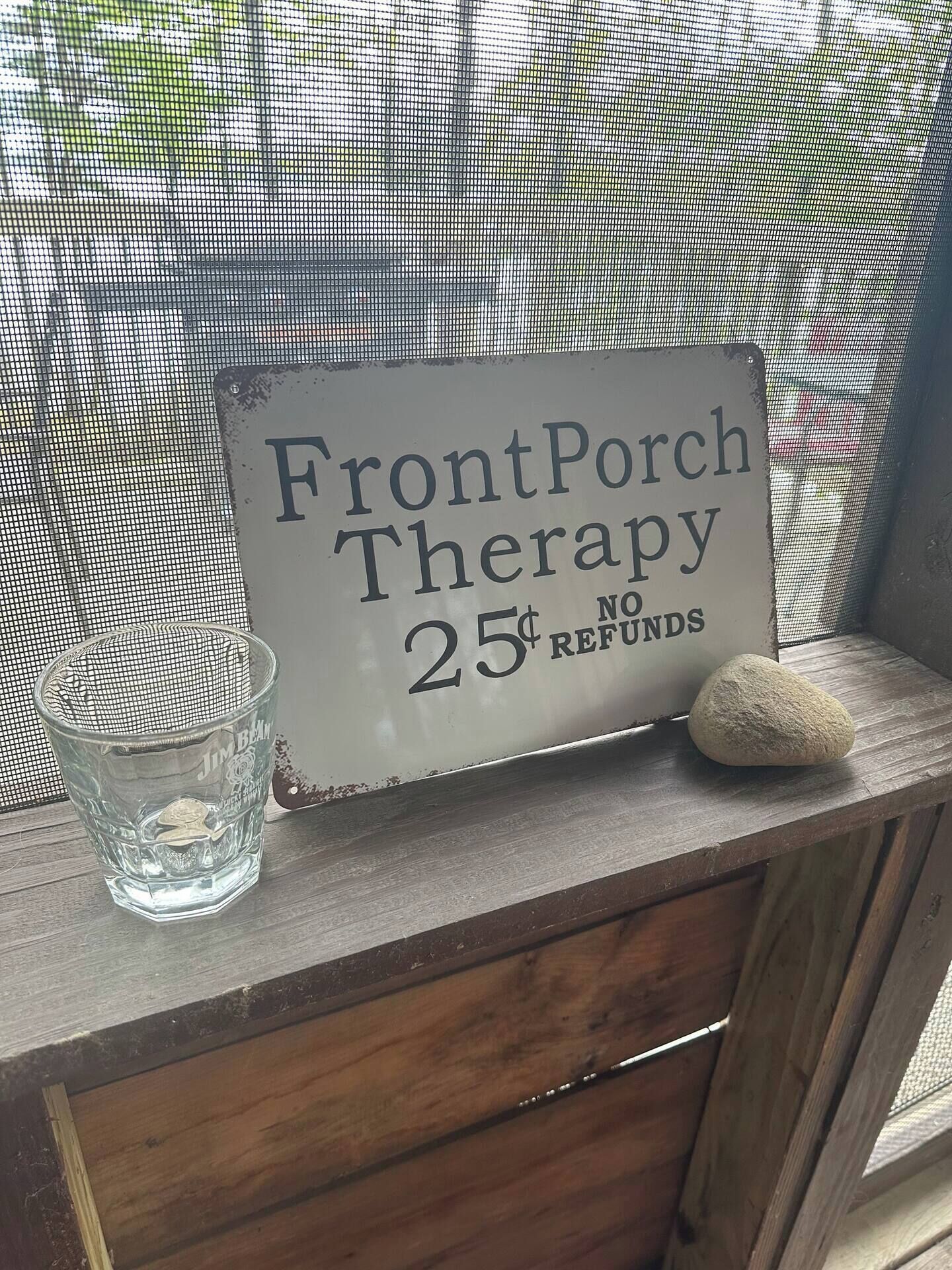A sign on a wooden ledge that reads "Front Porch Therapy 25¢ NO REFUNDS".