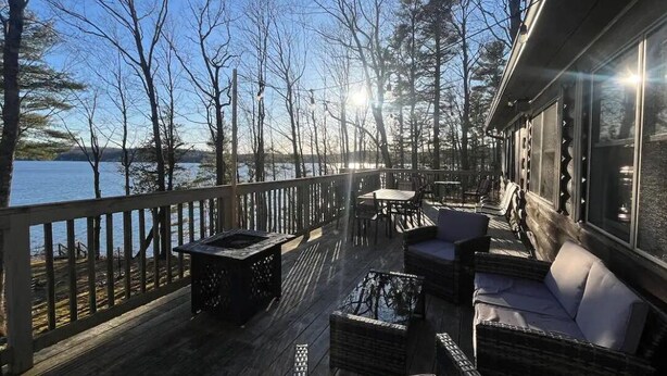 A wooden deck with outdoor furniture overlooking a body of water.