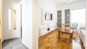Una sala de estar moderna con piso de madera, un televisor montado en la pared, una mesa de comedor con sillas y un sofá.