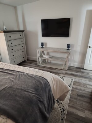 A bedroom with a bed, a dresser, a TV, and a small table. - Boca Jewels with Heated Jacuzzi (Boca Raton)