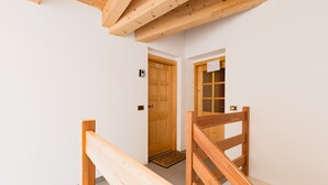 Eine Holztreppe führt zu einer Tür mit einem kleinen Fenster.