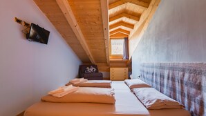 Ein Schlafzimmer mit Schlafgalerie, einem Bett mit Kissen, einem Schminktisch und einem an der Wand befestigten Fernseher.
