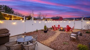 Un jardin avec un barbecue, des meubles d’extérieur et une guirlande lumineuse.