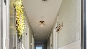 Un couloir doté d’un plancher en bois, de murs blancs et d’un luminaire au plafond.