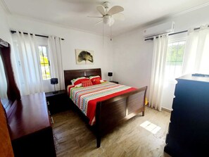A bedroom with a wooden bed, a ceiling fan, a desk, and a dresser. - Magic Cortesea luxury beach (Punta Cana)