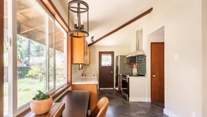 Une cuisine moderne équipée d’un four encastré, d’un four à micro-ondes et d’un évier. On y trouve également un banc en bois et une plante en pot près de la fenêtre.