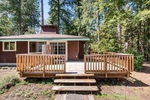 A cabin with a wooden deck, a chimney, and a large window. - Lupine Glen: Community Pool, Wifi, Fire, Deck! (Rhododendron)