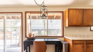 Une cuisine avec un plan de travail en bois, une table à manger noire et un luminaire suspendu.