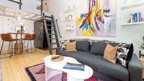 A modern living room with a grey sofa, a white coffee table, and a colorful abstract painting on the wall. - Vibrant Central Telluride Studio w Hot Tub (Telluride)