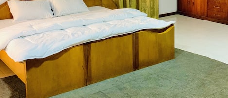 Een slaapkamer met een groot bed, een plafondventilator, een schilderij aan de muur en een houten kledingkast.