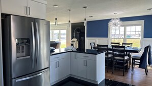 Een moderne keuken met roestvrijstalen apparatuur, witte kasten en een zwart aanrecht.