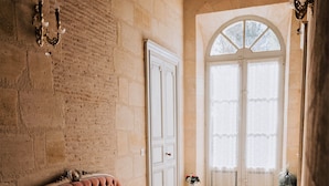Una habitación con piso de madera, un sofá tapizado rojo, una puerta blanca y un ventanal grande de arco.