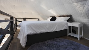 Une chambre à coucher avec un lit, une table de chevet, une fenêtre et une vue sur l’extérieur.