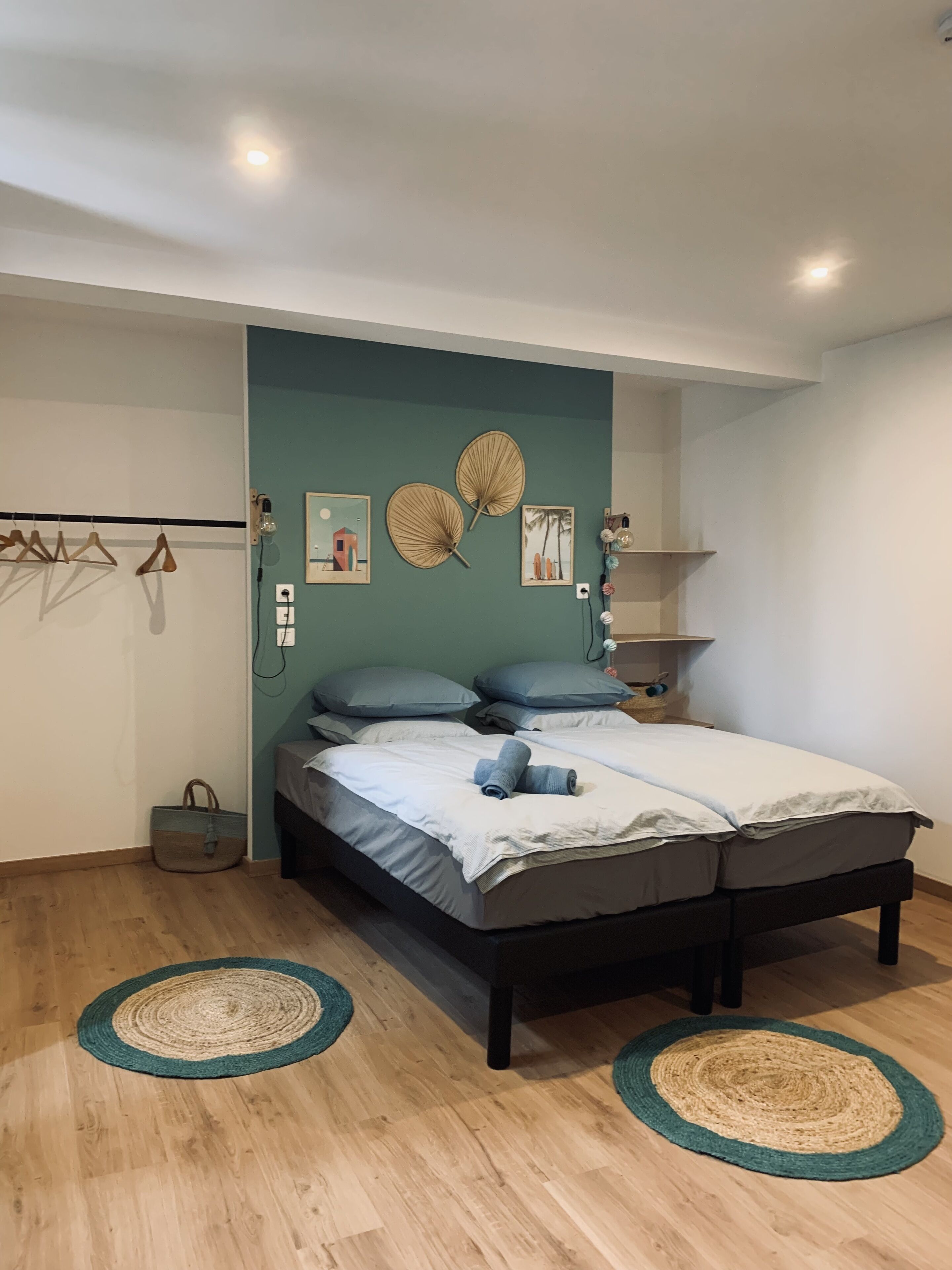 Une chambre à coucher avec un lit, une étagère fixée au mur et un porte-manteau suspendu.