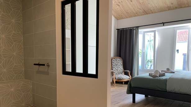 Ein Schlafzimmer mit einem Bett, einem Sessel und einem Fenster mit Vorhängen.