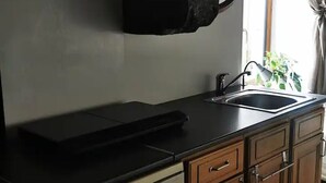 Une cuisine avec un plan de travail noir, un évier et des armoires en bois.