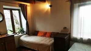 Une chambre à coucher avec un lit, une commode, une fenêtre avec des rideaux et une plante.