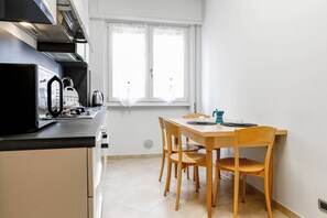 Une cuisine compacte comprenant une table et des chaises, une bouilloire et une machine à café.