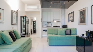 Ein modernes Wohnzimmer mit einem grünen Sofa, einem Couchtisch und einer Küchenzeile im Hintergrund.