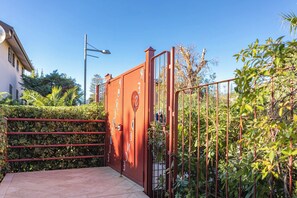 Een omheind toegangspunt met een metalen poort en een trap die naar een gebouw leidt.
