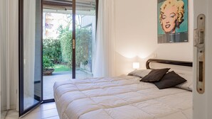 Ein Schlafzimmer mit einem Bett, einem Poster an der Wand und einer Glastür zu einem Außenbereich.