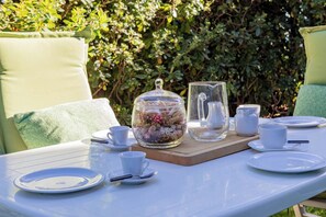 A table set outdoors with a glass container, cups, and plates.