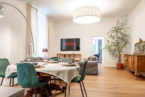 A modern living room with a dining area, a television displaying 'NETFLIX', and a large potted plant. - THE QUEEN'S APARTMENT - Ariston - Centro (Sanremo)