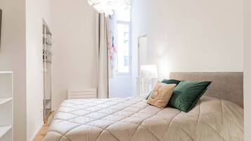 Une chambre à coucher avec un lit, une table de chevet, une lampe et une fenêtre avec des rideaux.