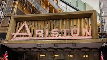 Un bâtiment dont la façade est ornée d’une enseigne au néon qui épelle le mot « ARISTON ».