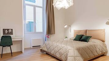 Una camera da letto con un letto, una scrivania, una sedia, una finestra con tende e una lampada a sospensione.