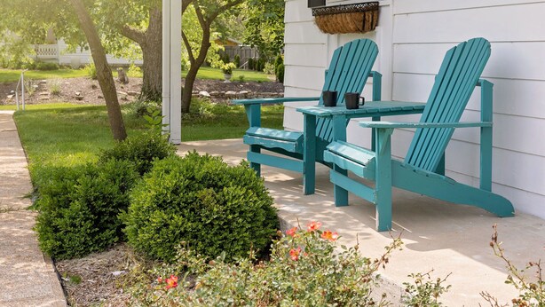 A porch with two turquoise Adirondack chairs and a small table, surrounded by well-maintained greenery and a white house with black shutters. - WELCOME TO THE OWL'S NEST - 2 BEDROOM HOME IN AUGUSTA, WINERIES & THE KATY TRAIL (Augusta)