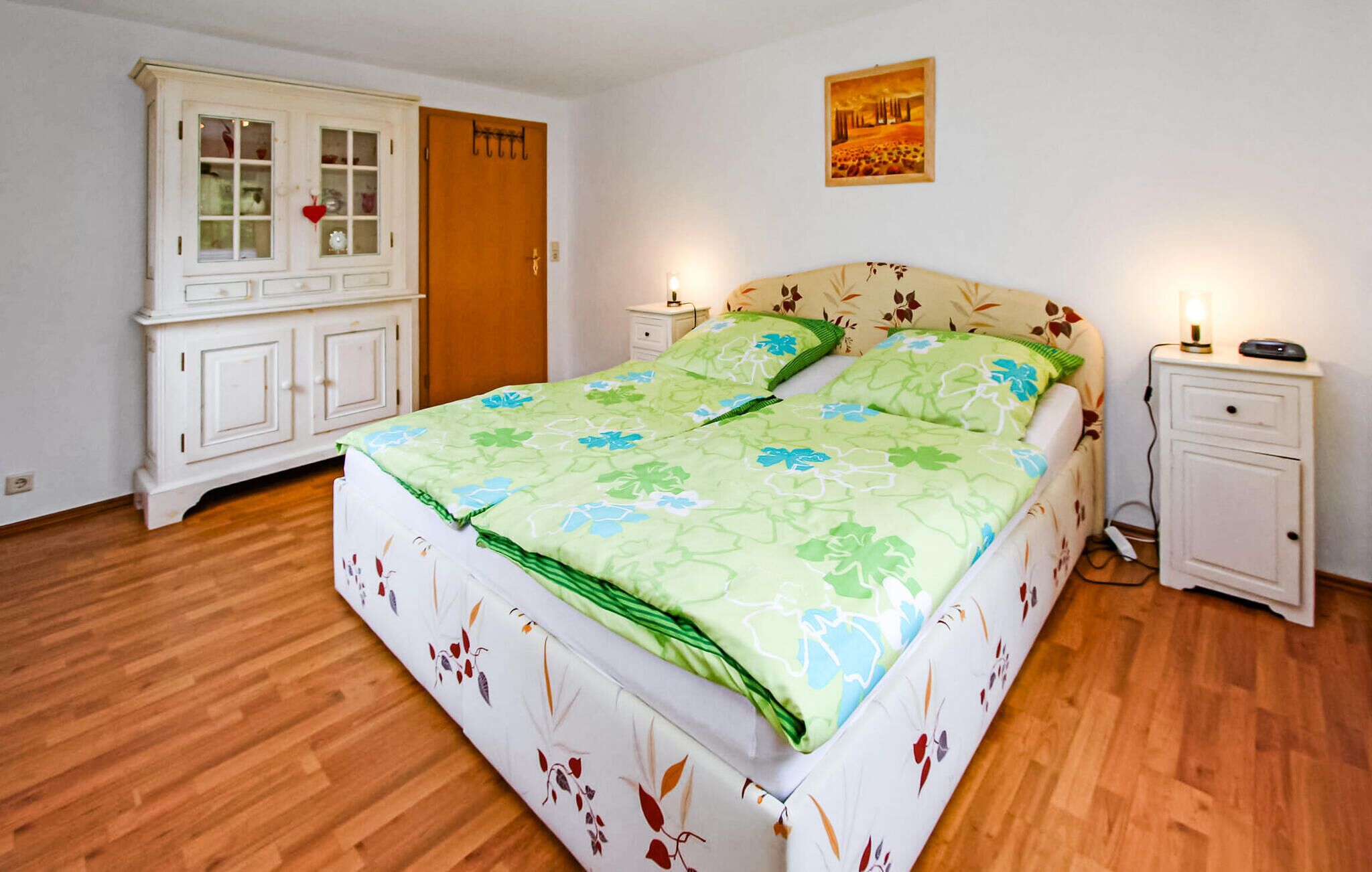 A bedroom with a bed, a nightstand, a dresser, and a door.