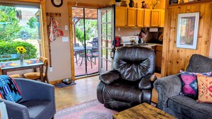 A cozy living room with a leather chair, a gray sofa, and a dining area with a table and chairs. - Bluff Bungalow w/ Patio, Dogs Welcome (Bluff)