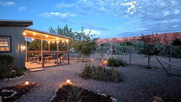 A covered outdoor seating area with tables and chairs, surrounded by a gravel path and plants. - Bluff Bungalow w/ Patio, Dogs Welcome (Bluff)