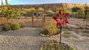 A garden with a wooden gate, a red pinwheel, and a rocky landscape with autumn foliage. - Bluff Bungalow w/ Patio, Dogs Welcome (Bluff)