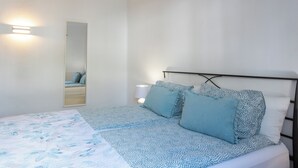 A bedroom with a bed, a bedside table with a lamp, a wall-mounted mirror, and a door. - Villa Blanca, Fkk-apartment Nr. 2 in Charco del Palo mit Schwimmbad, Meernähe (Charco del Palo)