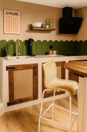 A kitchen with a wooden counter, a sink, a coffee machine, a hanging light, and a wicker chair. - Gîte 12 Personnes, Sauna, Billard, Baby-foot, Bain à Remous, Terrasse, Barbecue (Lapoutroie)