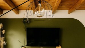 A modern living room with a wooden ceiling, a large flat-screen TV, a wooden coffee table, and two green sofas. - Gîte 12 Personnes, Sauna, Billard, Baby-foot, Bain à Remous, Terrasse, Barbecue (Lapoutroie)