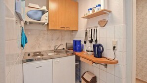 Une cuisine compacte équipée d’un four à micro-ondes encastré, d’un évier, d’une machine à café et d’une bouilloire.
