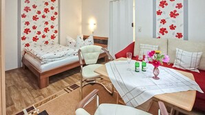 Une pièce comprenant un lit, un canapé, une table avec un vase de fleurs et un luminaire fixé au mur.