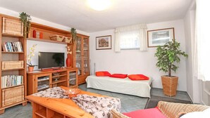 Una habitación acogedora con televisión, estantería, cama y muebles de mimbre.