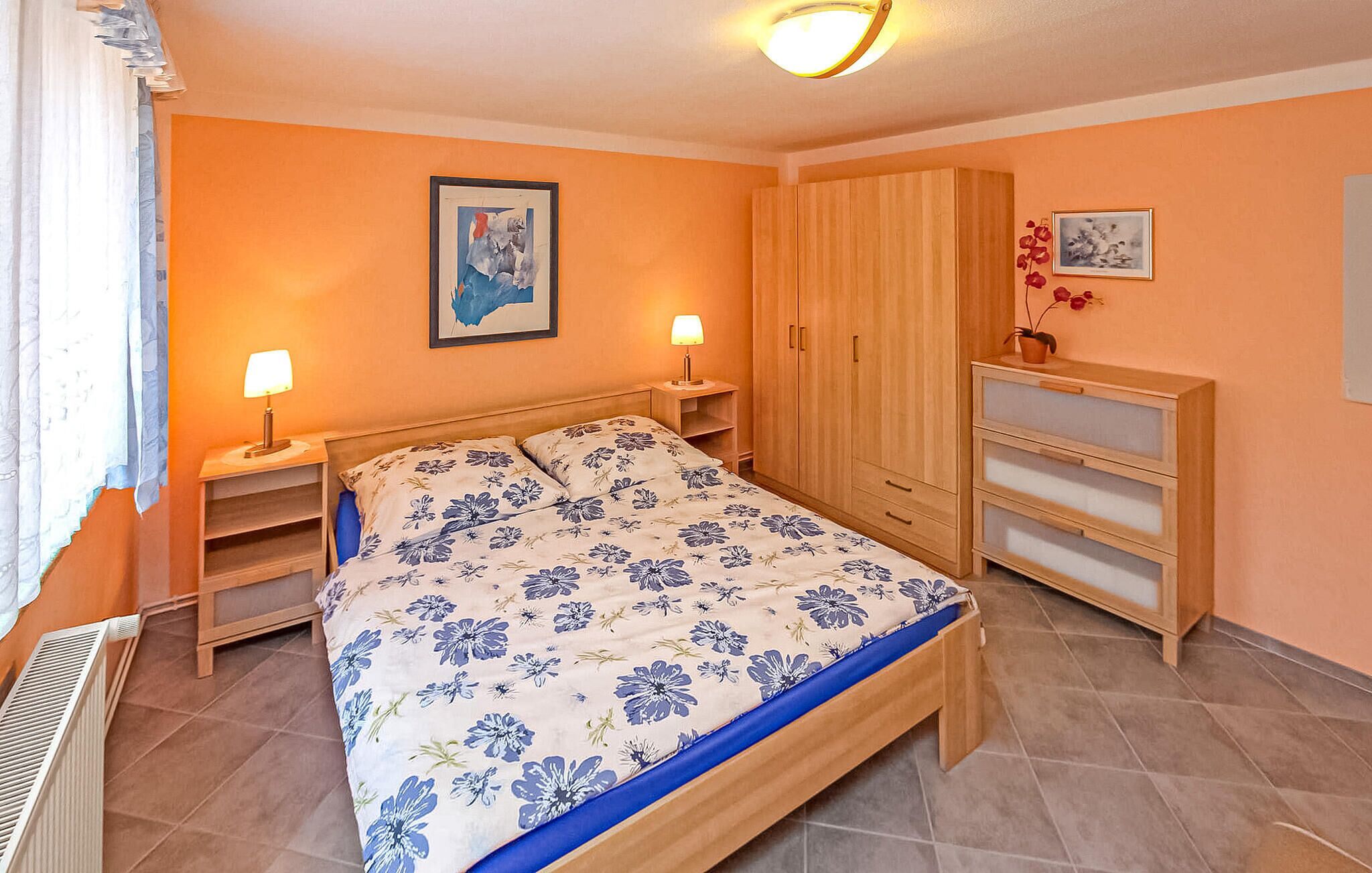 Une chambre à coucher comprenant un lit, deux tables de chevet, une armoire et un radiateur.