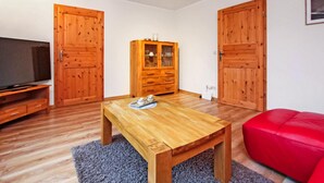 A room with wooden flooring, a wooden table with a tray of eggs, a red sofa, and wooden wardrobes.