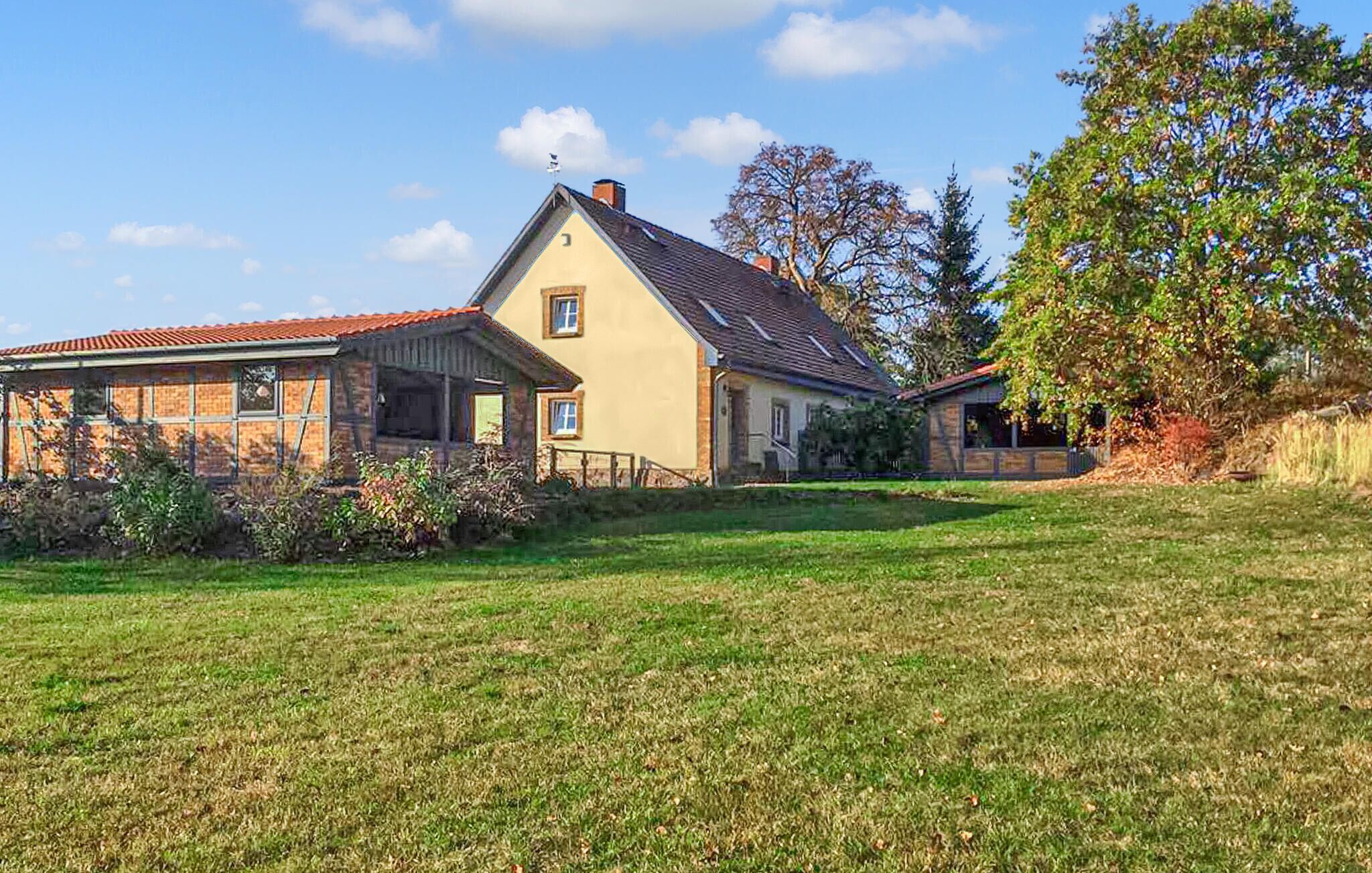 Une maison à deux étages, avec un toit en pente, une cheminée et un petit porche.