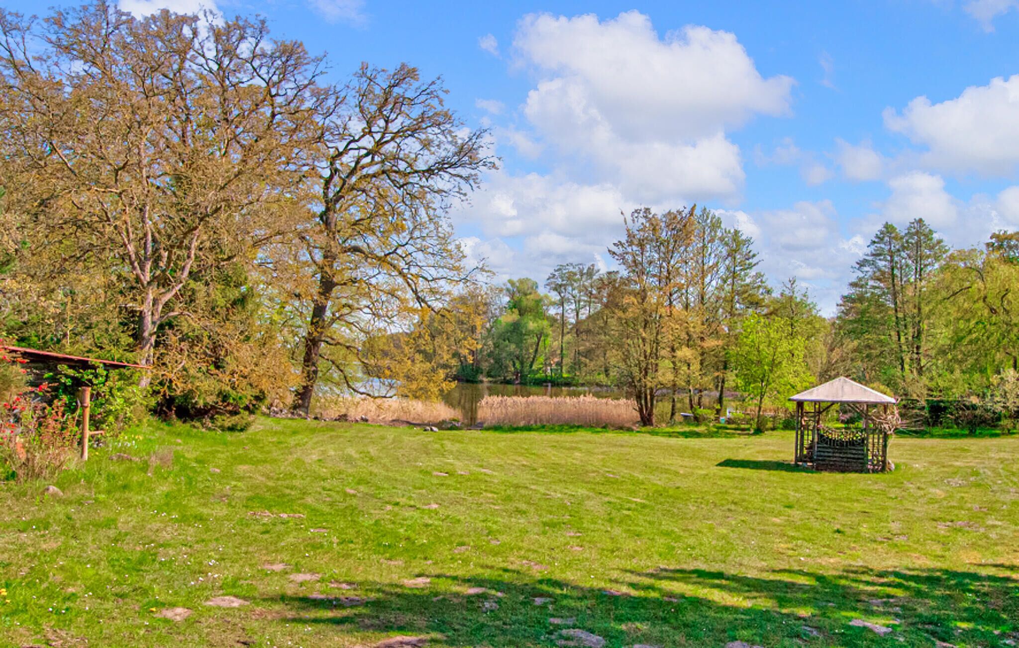 A grassy field with a gazebo and trees.